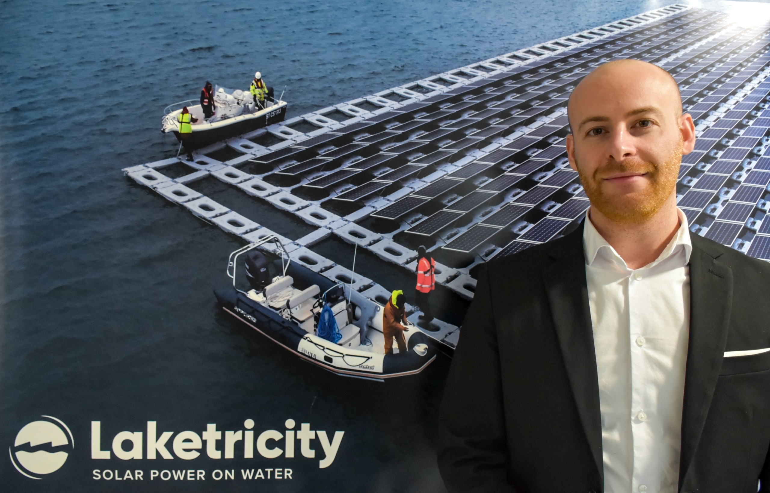 Giacomo Barbi standing in front of a Laketricity's project poster